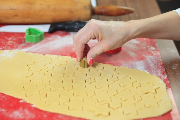 Jovens mãos cortando massa de gengibre em cozinha moderna