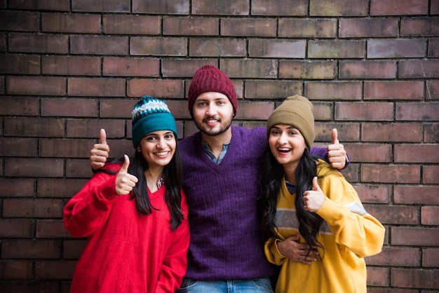 Jovens modelos asiáticos indianos ou amigos posando vestindo suéter de lã colorido e chapéus