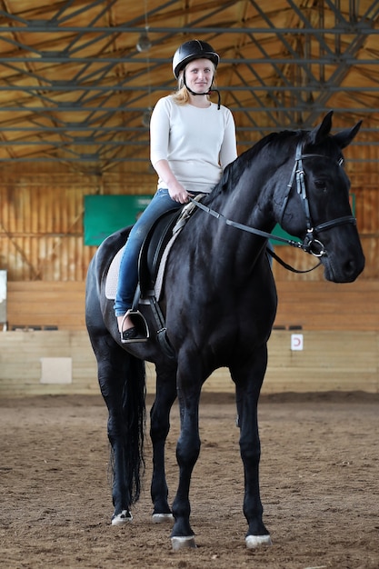 Jovens montados em um cavalo treinando em uma arena de madeira