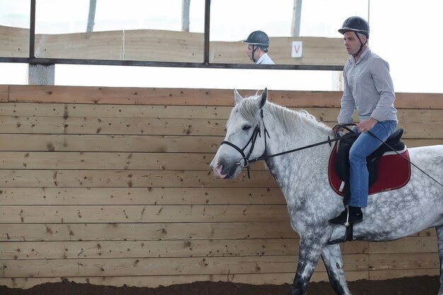 Foto jovens montados em um cavalo treinando em uma arena de madeira