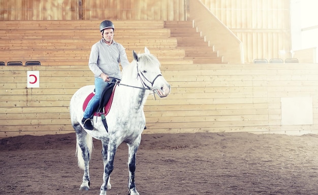 Jovens montados em um cavalo treinando em uma arena de madeira