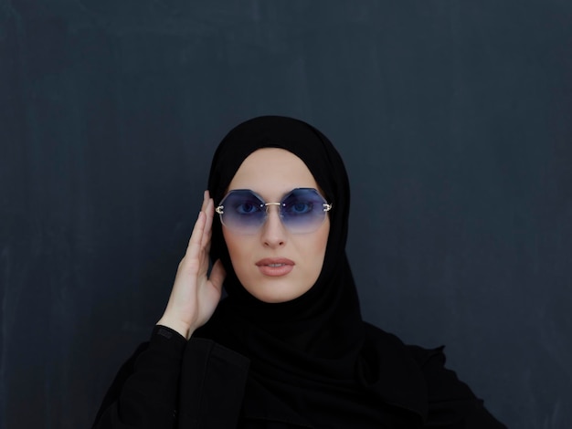 Jovens muçulmanos em roupas tradicionais ou abaya e óculos de sol posando na frente do quadro negro. Mulher árabe representando estilo de vida árabe moderno, moda islâmica e conceito de Ramadan kareem