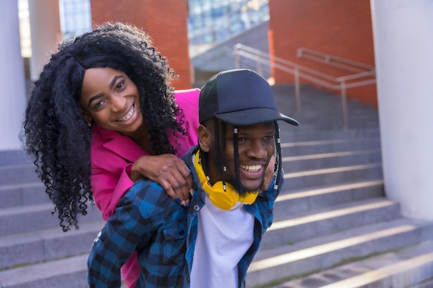 Jovens mulheres afro-americanas no estilo de vida da cidade de amigos abraçaram a caminhada ao pôr do sol