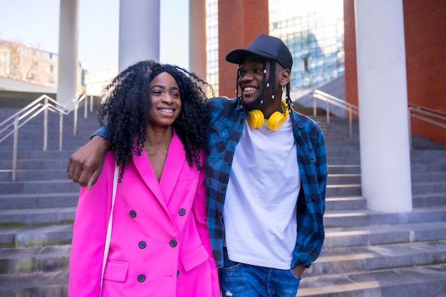 Jovens mulheres afro-americanas no estilo de vida da cidade de amigos abraçaram caminhar sorrindo