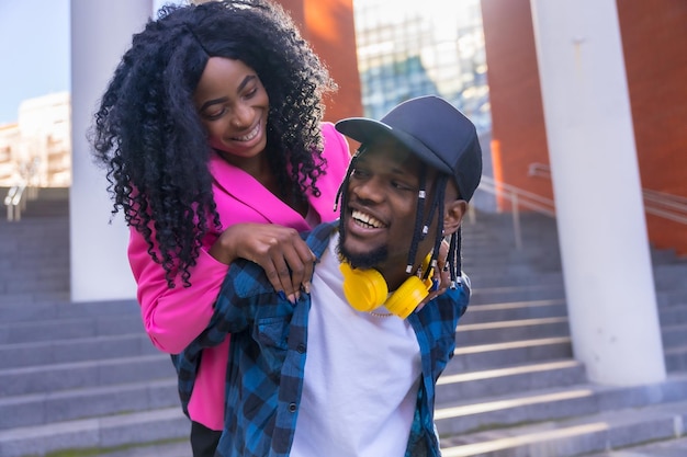 Jovens mulheres afro-americanas no estilo de vida da cidade de amigos andando em cima do cara se divertindo