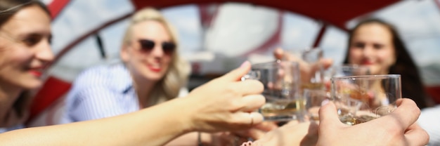 Jovens mulheres alegres em um iate tilintam de óculos e namoradas se divertem no barco