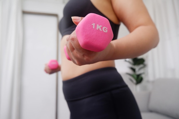 Jovens mulheres asiáticas fazendo exercícios em casa usando halteres para exercitar os braços e a parte superior do corpo