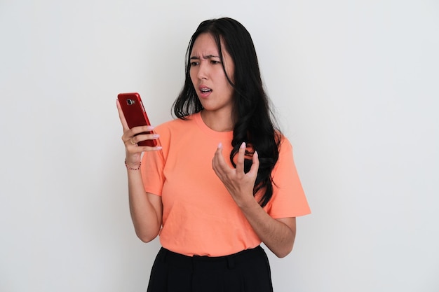 Foto jovens mulheres asiáticas olhando para o telefone e mostrando expressão de raiva