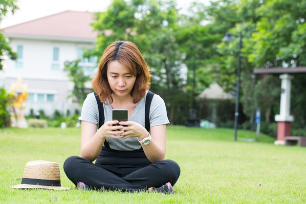 Jovens mulheres asiáticas usam telefone inteligente para chamadas e massagens para a amiga.