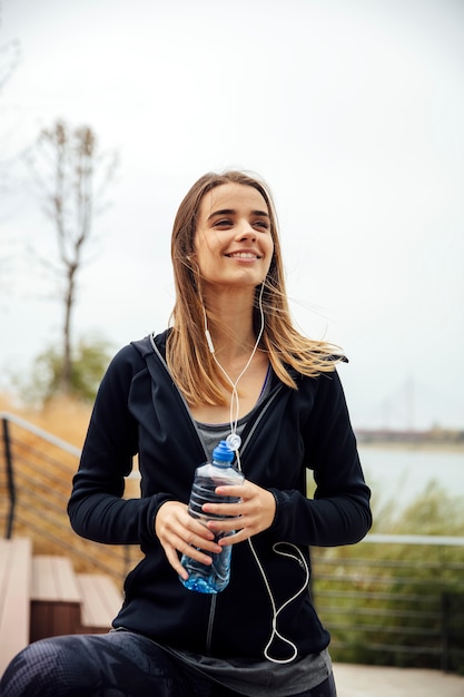 Jovens mulheres bonitas, descansando e bebendo água depois de fazer exercícios