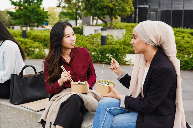 Jovens mulheres de negócios multirraciais comendo comida saudável ao ar livre