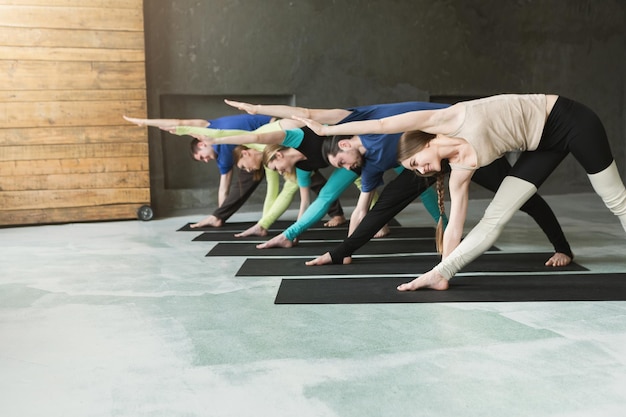 Jovens mulheres e homens na aula de ioga, exercícios de alongamento. Pose para relaxar. Estilo de vida saudável no clube de fitness, copie o espaço