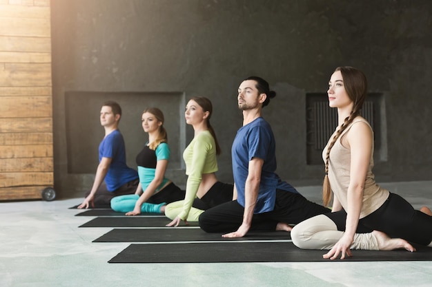 Jovens mulheres e homens na aula de ioga, exercícios de meditação. Pose de lótus para relaxamento. Estilo de vida saudável no clube de fitness, copie o espaço