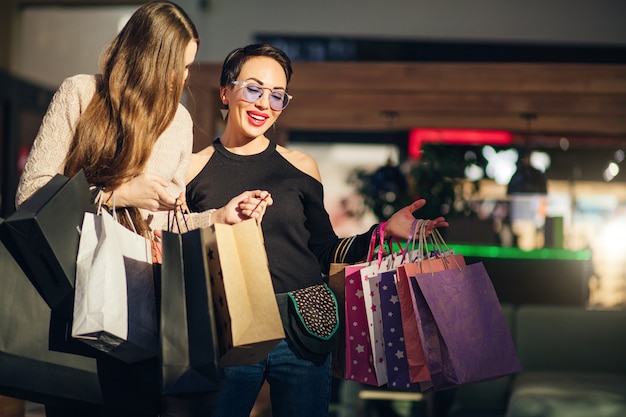 Jovens mulheres olhando para sacolas de compras após a visita no shopping