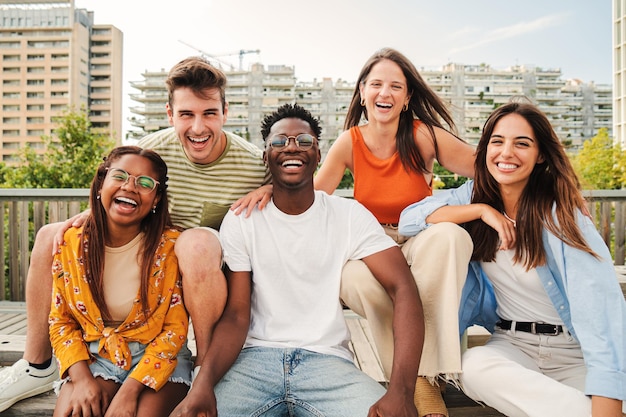 Jovens multirraciais felizes sorrindo juntos olhando para a câmera cinco amigos adolescentes se divertindo e rindo tirando fotos do lado de fora na rua da cidade Conceito de estilo de vida