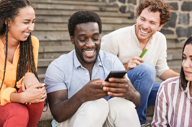 Jovens multirraciais usando smartphone na cidade - amigos da geração Y se divertindo ao ar livre