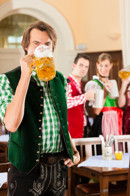 Jovens no Tracht tradicional da Baviera no restaurante ou pub