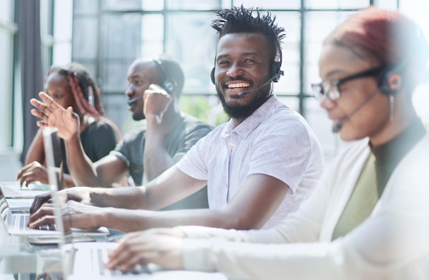 jovens operadores de call center sentam-se em frente a um laptop e ajudam a resolver problemas