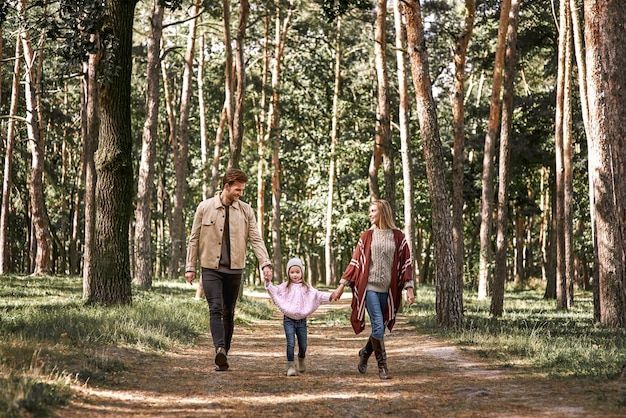 Jovens pais com filha na floresta de outono