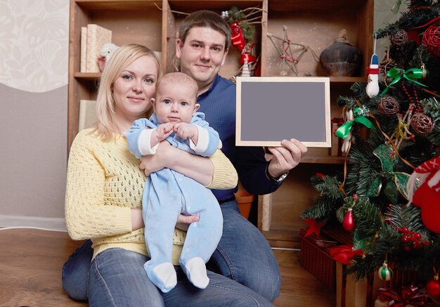 Foto jovens pais felizes mostrando um cartão de natal em branco