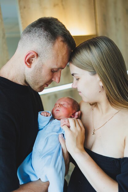 Foto jovens pais felizes segurando seu bebê recém-nascido em seus braços romper em um menino recém- nascido bebê nas mãos de mãe e pai