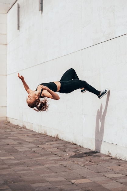 Jovens parkour e freerunning mulheres fazendo um backflip de uma parede