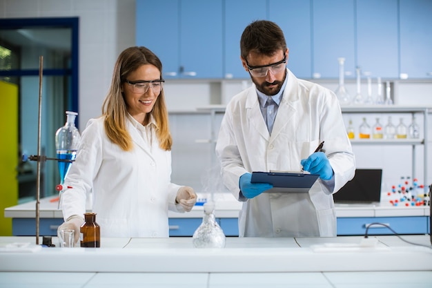 Jovens pesquisadores fazendo experimentos com fumaça sobre a mesa de um laboratório químico