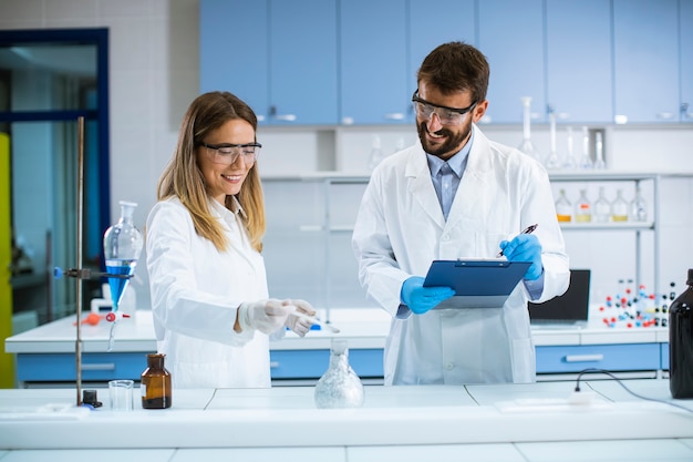 Jovens pesquisadores fazendo experimentos com fumaça sobre a mesa de um laboratório químico