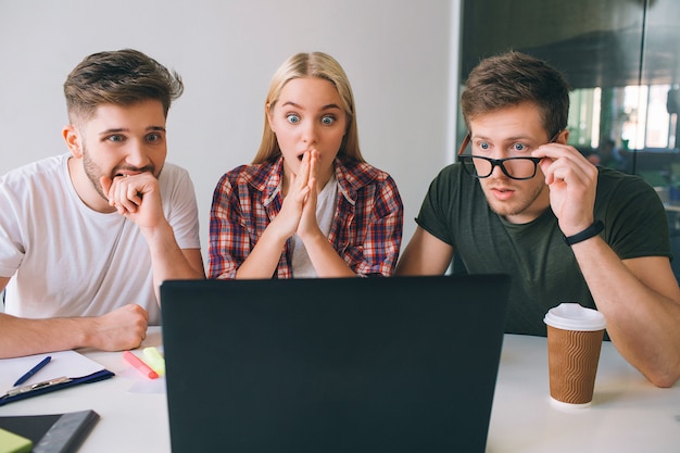 Jovens preocupados sentam-se juntos na sala e olham para a tela do laptop