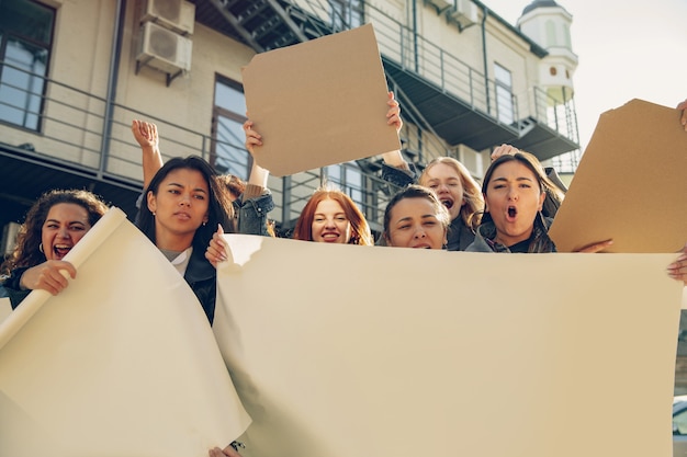 Jovens protestando pelos direitos das mulheres e igualdade nas ruas. Mulheres brancas têm reuniões sobre problemas no local de trabalho, pressão masculina, violência doméstica, assédio. Copyspace. Segurando pôsteres.