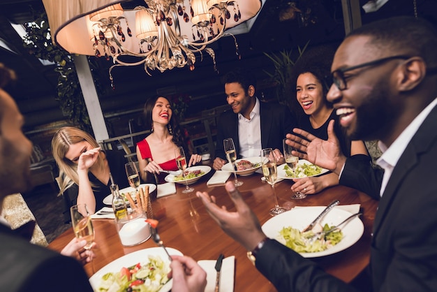 Jovens que bebem o álcool em um restaurante.