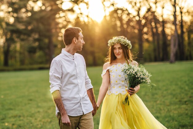 Foto jovens recém-casados felizes caminhando no parque ao pôr do sol