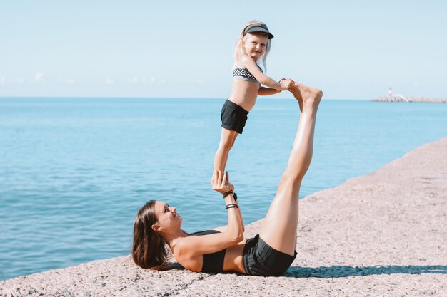 Jovens se encaixam mãe mãe com menina bonita, exercitar-se na praia de manhã juntos, estilo de vida saudável, família de esporte