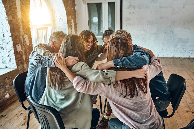 Jovens sentados se abraçando em reuniões de construção de equipes corporativas em sessões de terapia em grupo