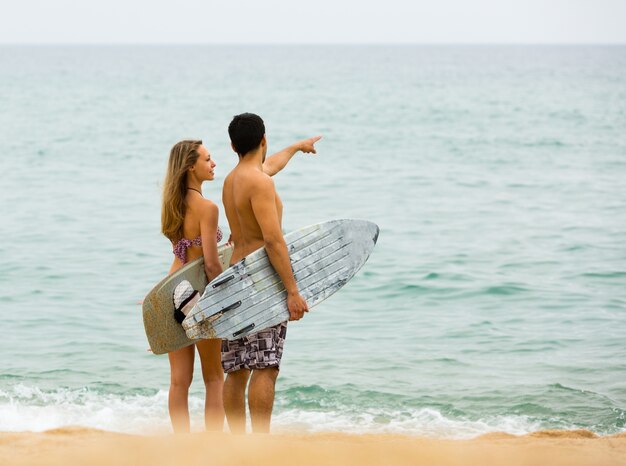 Foto jovens surfistas casal na praia