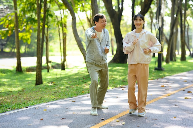 Jovial joven asiática corriendo con su padre en el parque Actividades familiares concepto de salud y bienestar