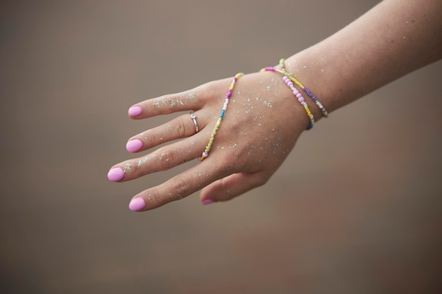 Joyas modernas con cuentas en la mano de la niña. Anillos y pulseras en la mano de la niña.