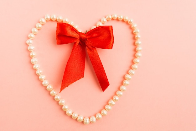 Joyas de perlas blancas en forma de corazón con lazo rojo