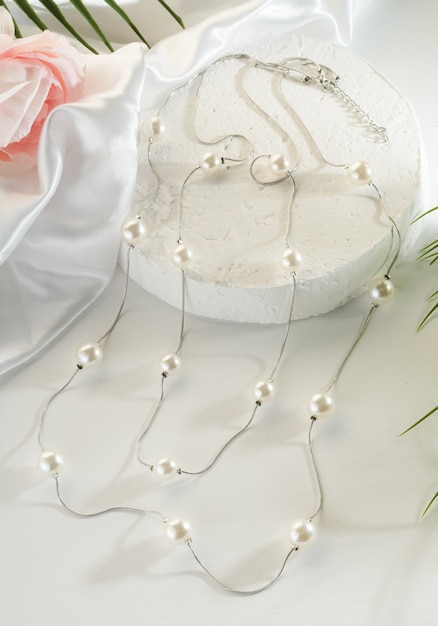 Foto joyería de moda - cadena de plata doble con perlas blancas sobre un fondo blanco de cerca