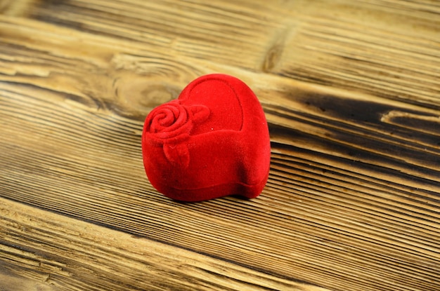 Joyero rojo en forma de corazón sobre una mesa de madera