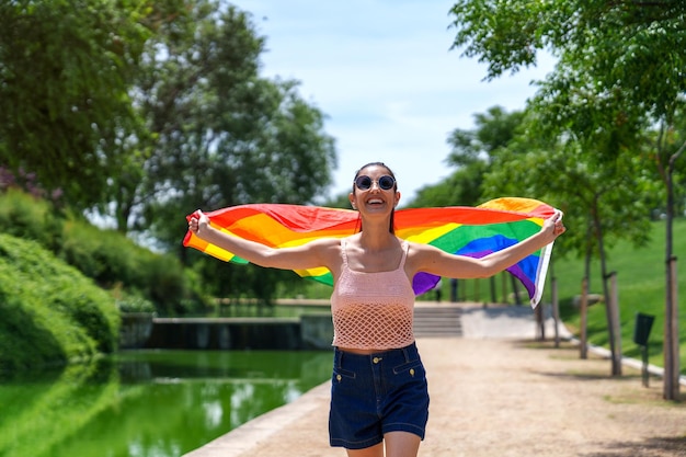 Joyful Brunette kaukasisches Model mit LGBT-Flagge im Green Park am Sunny River