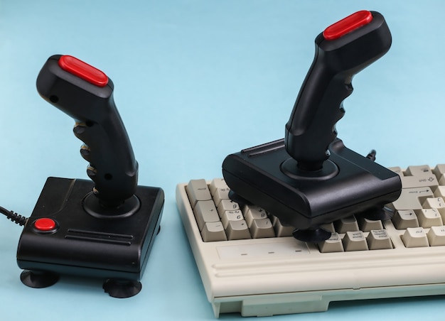 Joysticks retrô com teclado de pc antigo. Fundo azul. Atributos anos 80, jogos