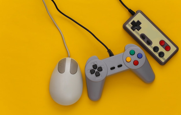 Foto joysticks retrô e mouse de pc em um amarelo. jogos retrô, dispositivos de jogos, gadgets