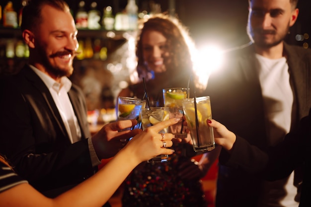 Jubeln und Cocktails trinken Gruppe von Freunden, die in einem Nachtclub feiern und Getränke anstoßen