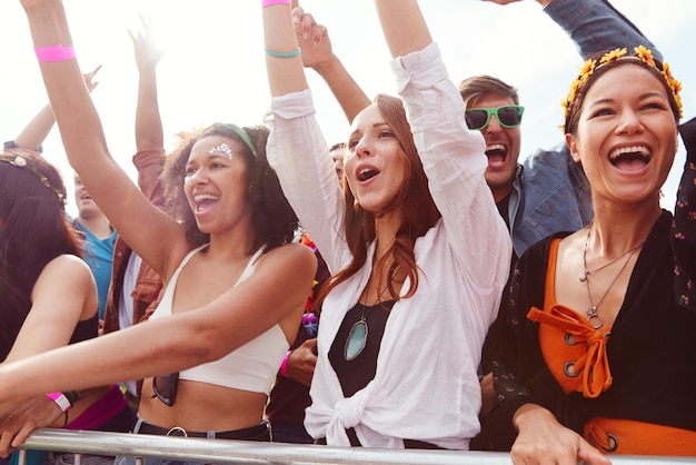 Foto jubelnde junge freunde im publikum hinter der barriere beim outdoor-festival, das musik genießt