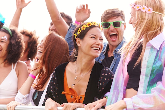 Foto jubelnde junge freunde im publikum hinter der barriere beim outdoor-festival, das musik genießt