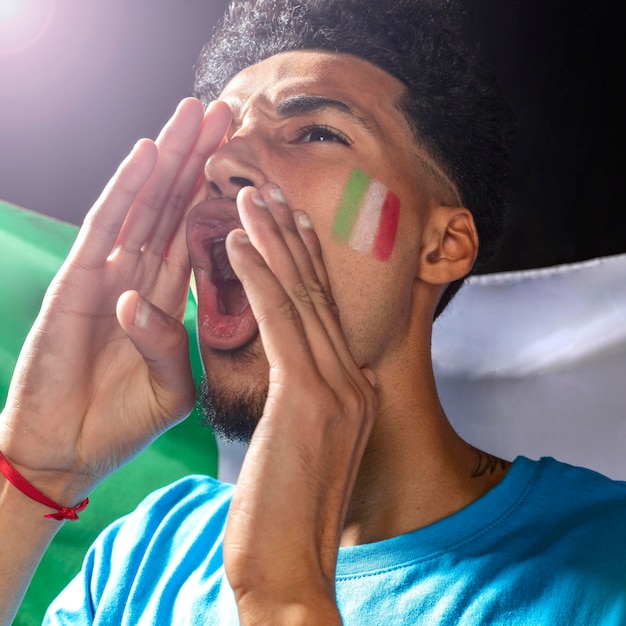 Foto jubelnder mann mit der italienischen flagge auf seinem gesicht