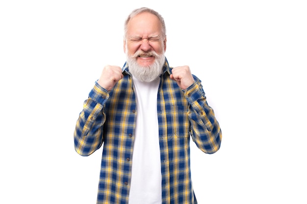 El jubilado mayor hombre de pelo gris con barba en una camisa sueña cubriendo sus ojos en un blanco