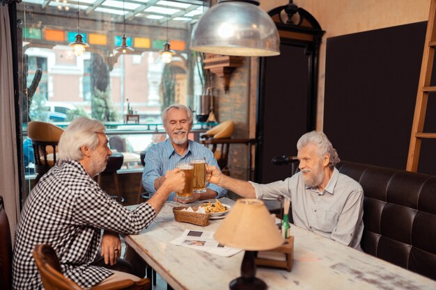 Jubilados relajantes. Tres jubilados que se sienten bien mientras se relajan y beben cerveza.