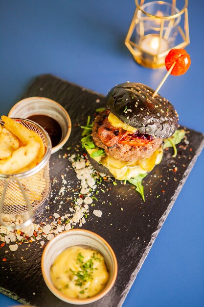 Jucy burger con papas fritas y soia sos en la mesa del restaurante. Comida sabrosa